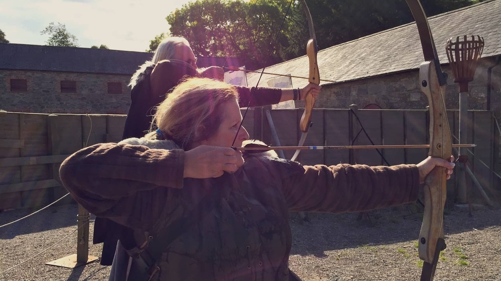 Bezoekers in kostuum oefenen boogschieten op de filmlocatie van Winterfell in County Down.