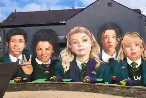 Colourful mural of five school pupils in Derry Girls, wearing uniforms and smiling in Derry~Londonderry.