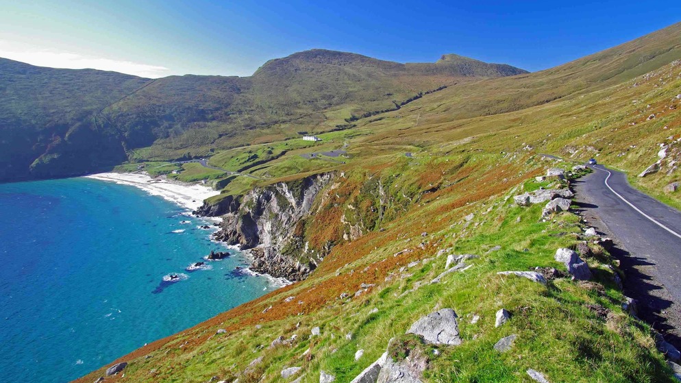 Küstenstraße oberhalb der Keem Bay, Achill Island, mit türkisfarbenem Wasser, Sandstrand und grünen Hügeln.