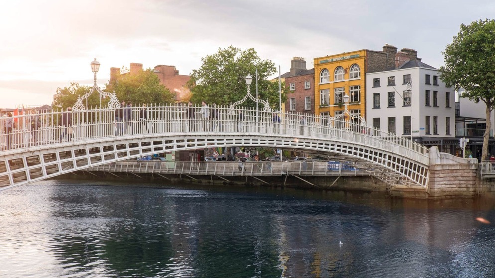 Le pont Ha'penny au coucher du soleil, avec des piétons et des bâtiments géorgiens, faisant la promotion du musicien folk irlandais Luke Kelly.