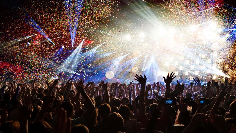 Pioggia di coriandoli sulla folla che festeggia a un festival di musica in Irlanda con luci di scena brillanti e energia.