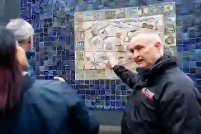 Una guida indica una mappa di opere d'arte su pavimento di piastrelle durante un tour guidato DC Tours a Belfast.