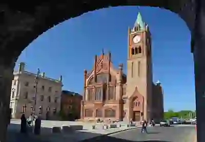La Guildhall di Derry~Londonderry con la sua torre dell'orologio, incorniciata da edifici storici, in una giornata di sole.