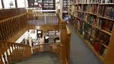 Veduta di una scala in legno che porta alla storica Linen Hall Library di Belfast, con scaffali pieni di libri antichi.