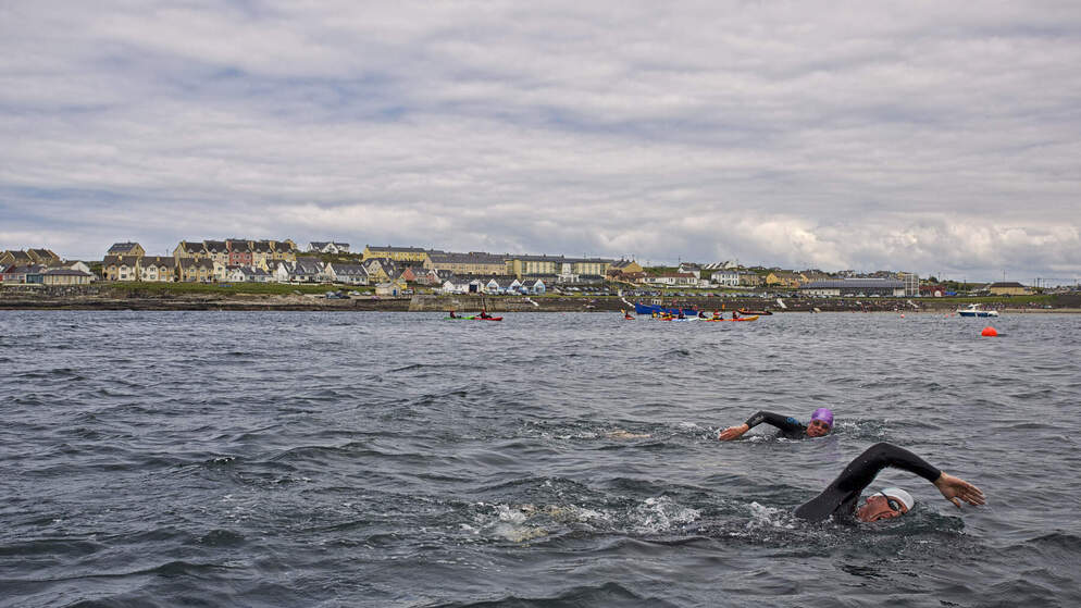 Swimmers in wetsuits and brightly coloured swim caps take part in an open water event off the coast of Lahinch, County Clare.