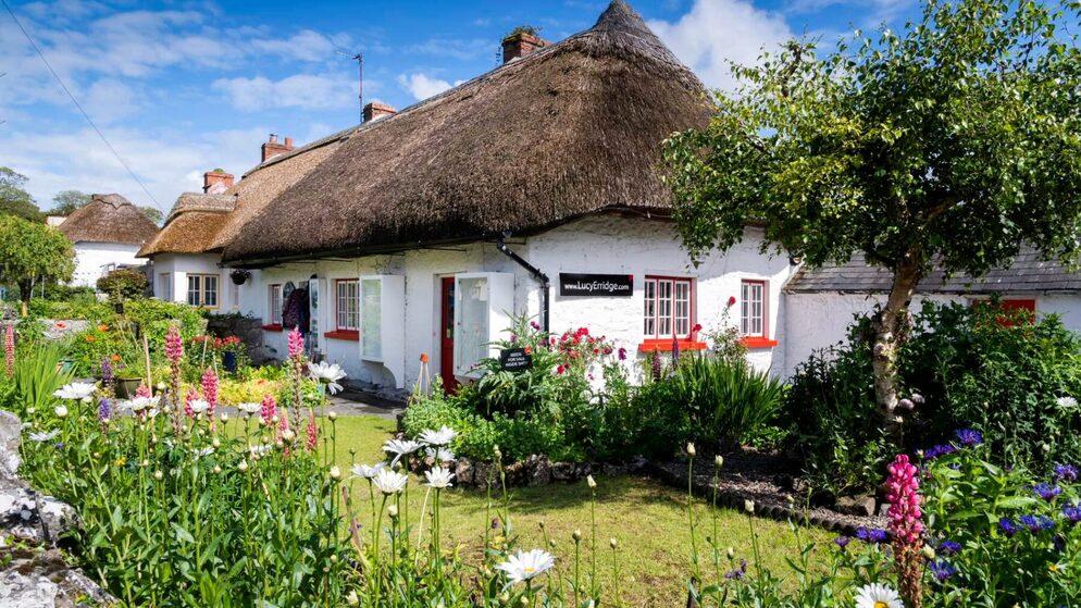 Chaumière au toit de chaume avec murs blanchis à la chaux et enseigne « Lucy Erridge » dans le village d’Adare, comté de Limerick.