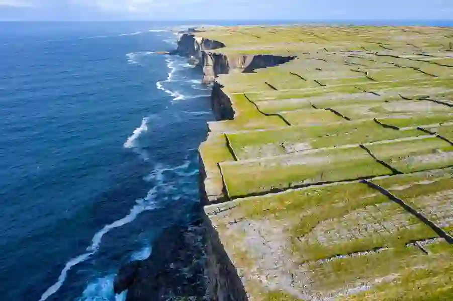 Aerial view of stone-walled fields stretching to dramatic sea cliffs on the Aran Islands, County Galway.
