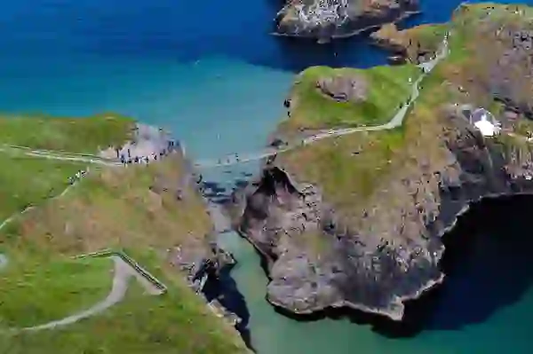 Bezoekers die de Carrick-a-Rede touwbrug boven de zee oversteken op de Causeway kustroute, county Antrim.