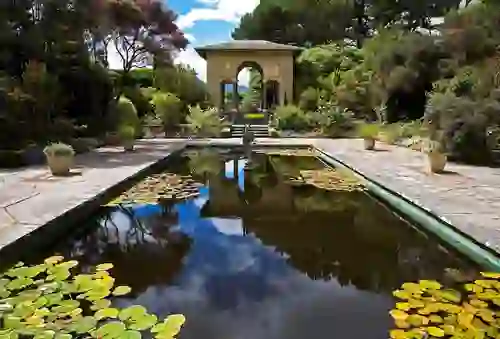 Italian Garden at Garnish Island with reflecting pool, lily pads and classical pavilion surrounded by lush planting.