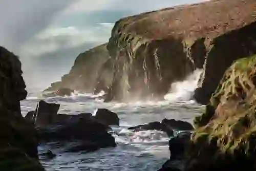 Waves crashing against rugged sea cliffs along the Wild Atlantic Way in County Cork.