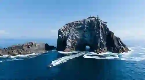Fast boat approaching the lighthouse on Fastnet Rock off the coast of County Cork.