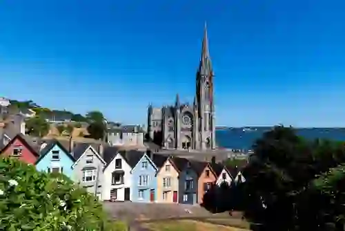St Colman’s Cathedral overlooking colourful houses and Cork Harbour in Cobh, County Cork.
