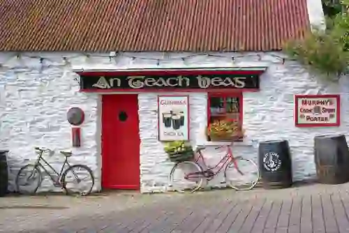 An Teach Beag traditional Irish pub in Clonakilty, West Cork, with whitewashed walls, red door and vintage bicycles outside.