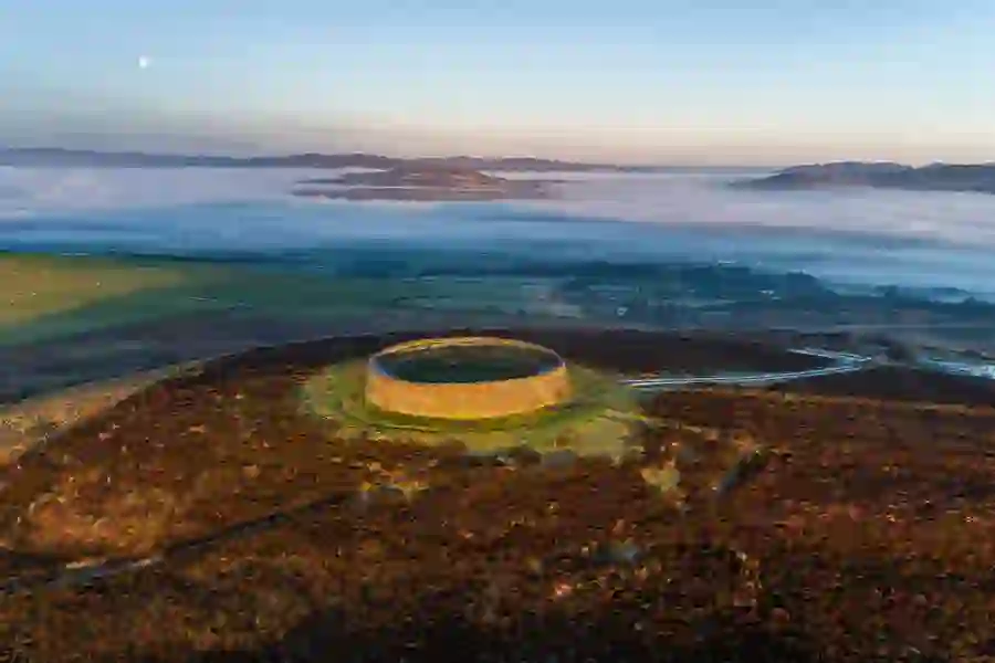 Luchtfoto van het ringfort An Grianán of Aileach bij zonsopgang, omgeven door mistige heuvels in county Donegal.