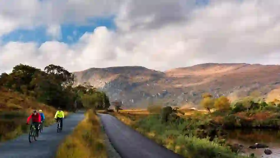 Een groep fietsers op een pad door Glenveagh National Park met ruige bergen en herfstbladeren, county Donegal.