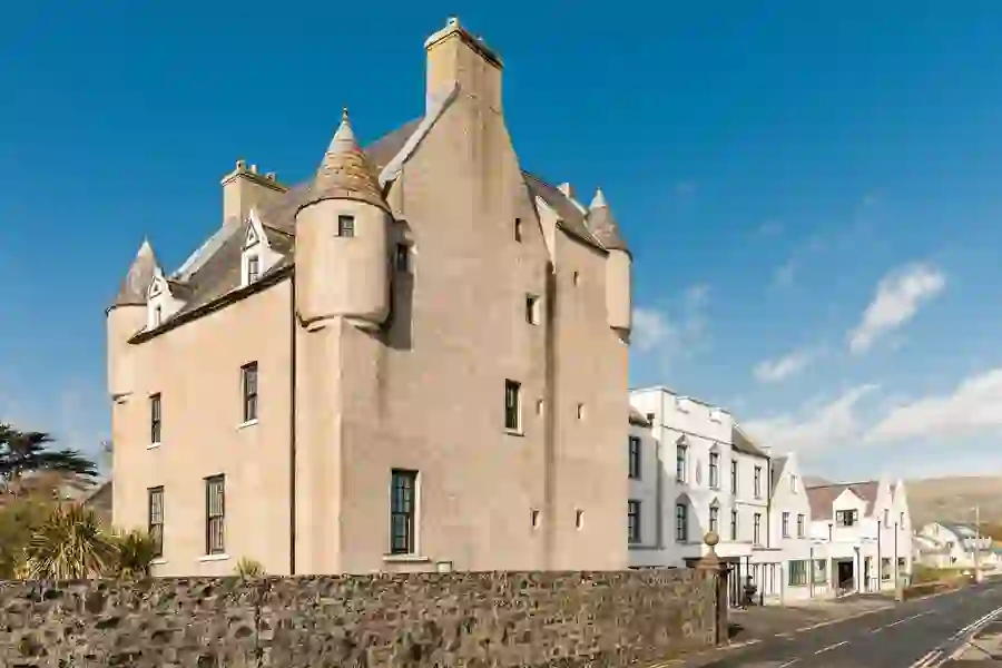 Het historische Ballygally Castle Hotel met zijn torentjes onder een blauwe lucht in Ballygally, county Antrim.