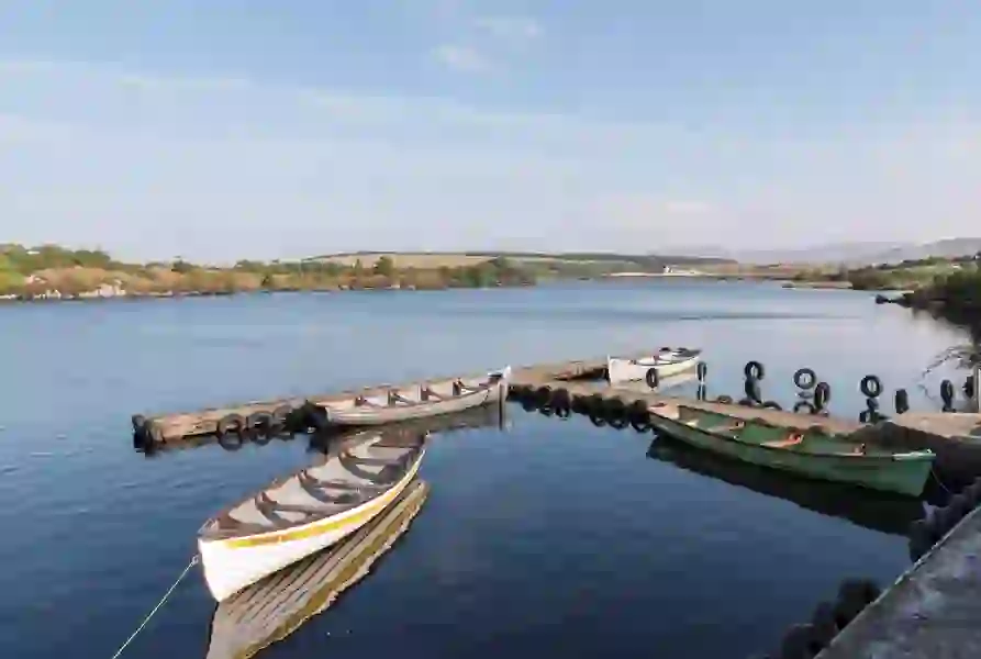 Traditionele houten boten liggen aangemeerd aan de stille aanlegsteiger van een rustig meer in de buurt van Dungloe in county Donegal.