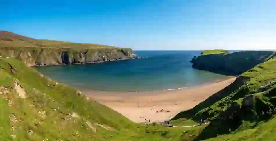 Het hoefijzervormige Silver Strand met goud zand en dramatische kliffen, county Donegal.