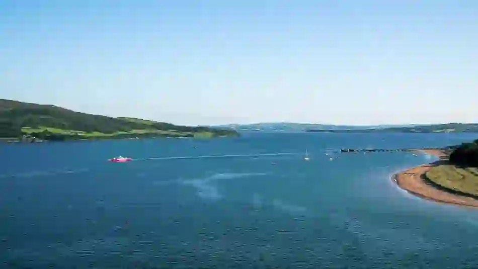 Luchtfoto van Rathmullan, county Donegal met een rode veerboot op Lough Swilly en groene heuvels die zich uitstrekken tot aan de horizon.