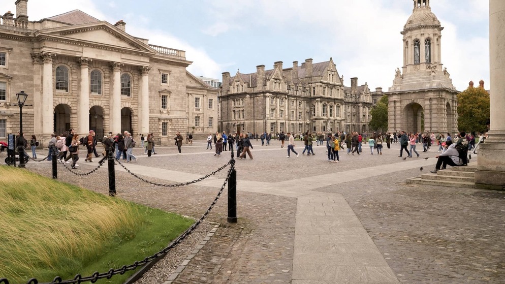 Students and visitors walking through the cobbled front square at Trinity College Dublin with the Campanile and historic buildings.