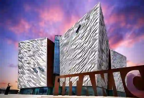 Das Titanic Belfast Museum mit seiner markanten, kantigen Fassade vor einem farbenfrohen Himmel bei Sonnenuntergang im Titanic Quarter von Belfast.