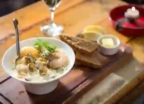 Meeresfrüchte-Chowder mit Garnelen und Muscheln, serviert mit Vollkornbrot und Butter auf einem Holztisch im Johnnie Fox's Pub in den Dublin Mountains.
