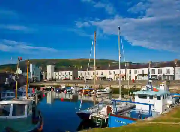 Fischerboote im Hafen von Carnlough, dahinter farbenfrohe Häuser des Dorfes.