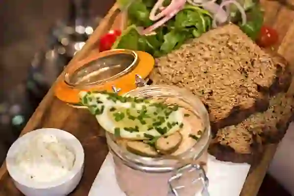 Räucherlachs-Pâté serviert mit Vollkornbrot, eingelegtem Gemüse und Salat auf einem Holzbrett im Crabby Jo's Seafood Restaurant, Howth, Grafschaft Dublin.