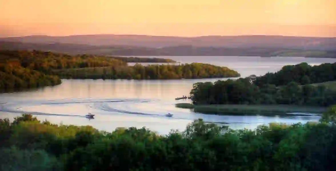 Deux bateaux naviguent dans la paisible région des lacs de Fermanagh au coucher du soleil.