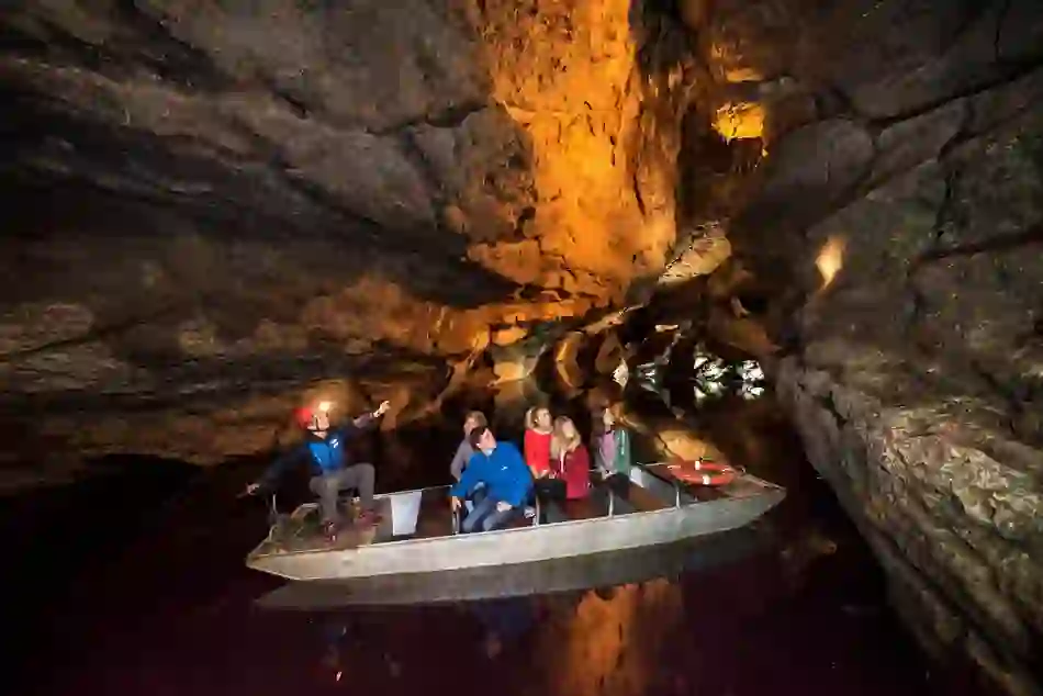 Guide menant une visite en bateau à travers les passages illuminés des grottes de Marble Arch dans le comté de Fermanagh.