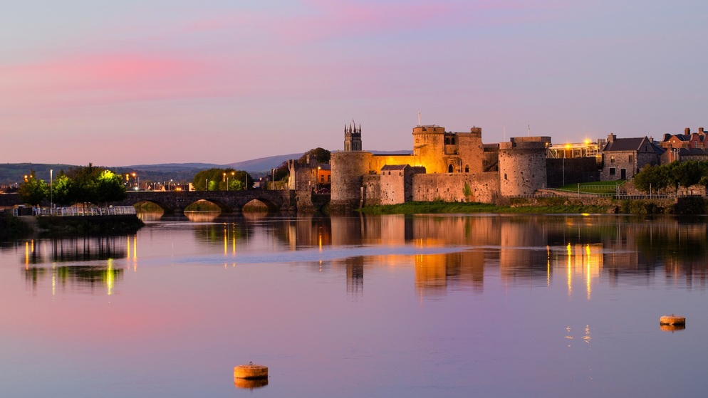 Le château de Jean sans Terre illuminé au crépuscule sur Le Shannon, une attraction emblématique de la ville de Limerick.