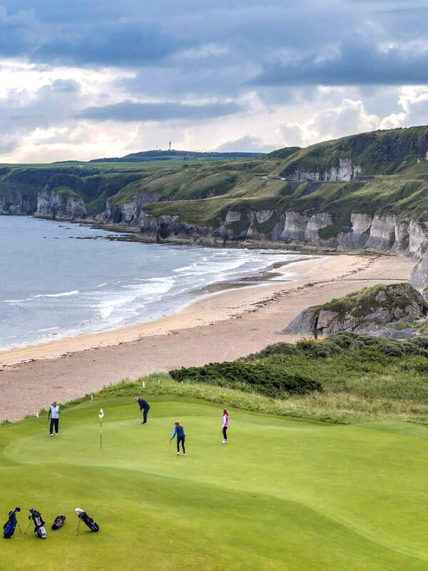 Des golfeurs jouant au club de golf Royal Portrush avec des falaises en arrière-plan.