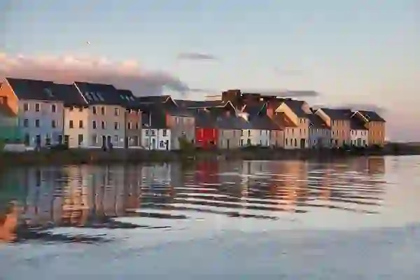 Casas de colores a lo largo de The Claddagh reflejadas en el río Corrib al atardecer en la ciudad de Galway.