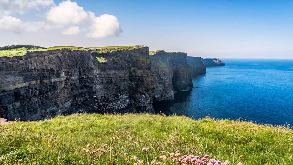 Acantilados de Moher que se elevan sobre el Océano Atlántico bajo un cielo azul brillante en el condado de Clare.
