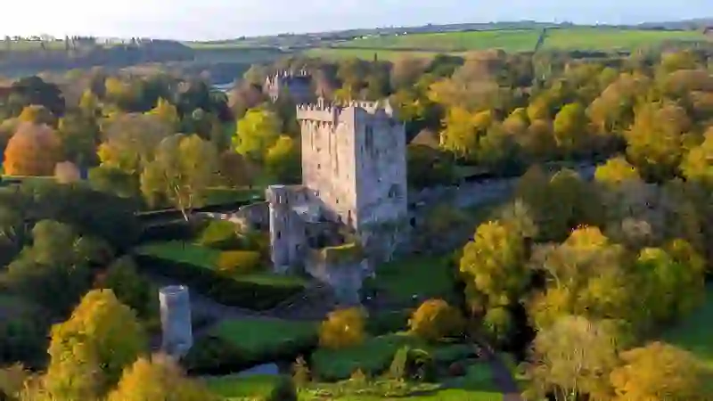 Aerial view of Blarney Castle and gardens surrounded by autumn trees in County Cork.