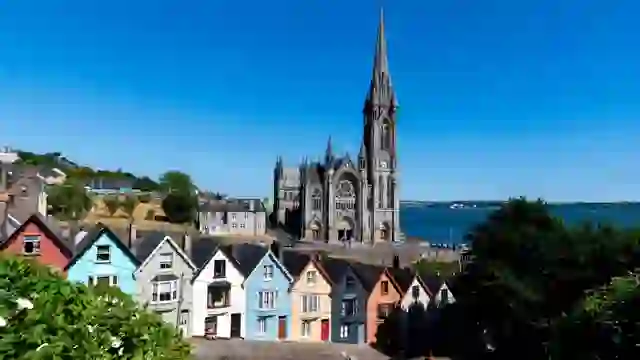Row of colourful terraced houses in front of St Colman's Cathedral in Cobh, County Cork.