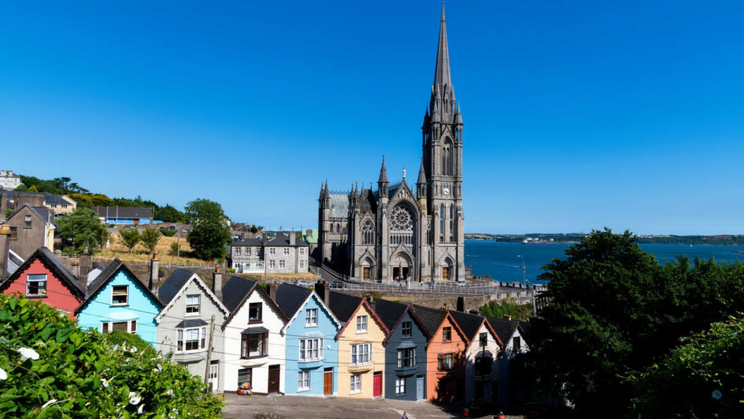 Row of colourful terraced houses in front of St Colman's Cathedral in Cobh, County Cork.