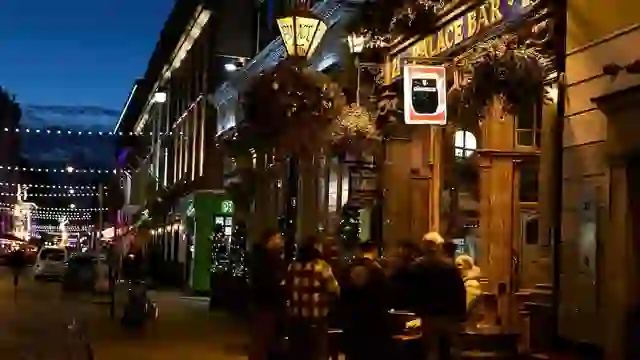 The Palace Bar on Fleet Street in Dublin at night, glowing with warm lights and outdoor tables.