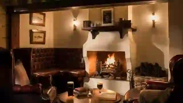 Cosy lounge at the Bushmills Inn with leather seating, open fireplace and pints on a wooden table.