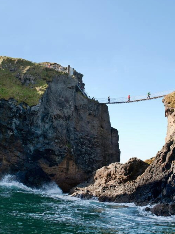 Waves crashing below Carrick-a-Rede Rope Bridge between steep basalt cliffs on the Causeway Coast.