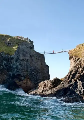 Waves crashing below Carrick-a-Rede Rope Bridge between steep basalt cliffs on the Causeway Coast.