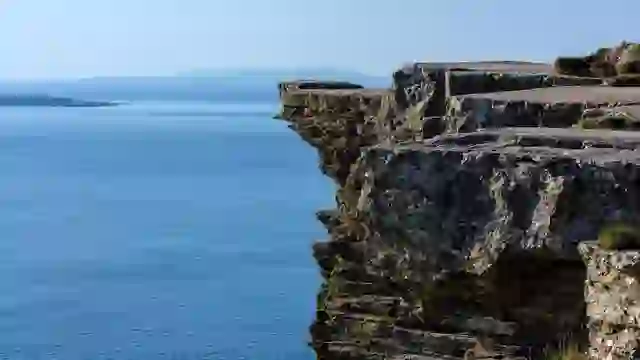 Cliffs of Moher overlooking the Atlantic Ocean with rugged limestone cliffs under a clear blue sky.