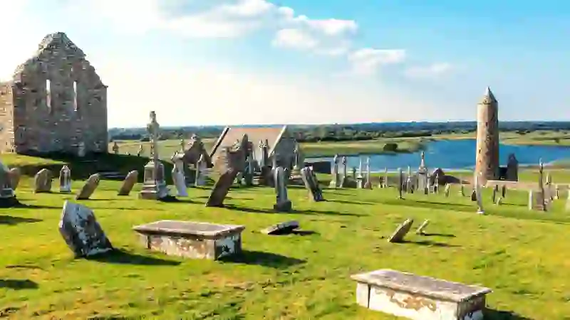 Grabsteine ​​und Kirchenruine in Clonmacnoise mit Blick auf den Fluss Shannon in der Grafschaft Offaly.