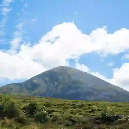 Der Berg Croagh Patrick ragt unter strahlend blauem Himmel in der Grafschaft Mayo, Irland, über die grüne Landschaft empor.