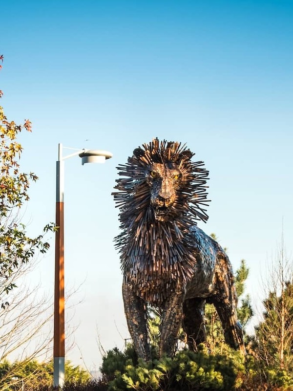 Große Metallskulptur eines Löwen namens Aslan zwischen Bäumen auf dem CS Lewis Square in Belfast.