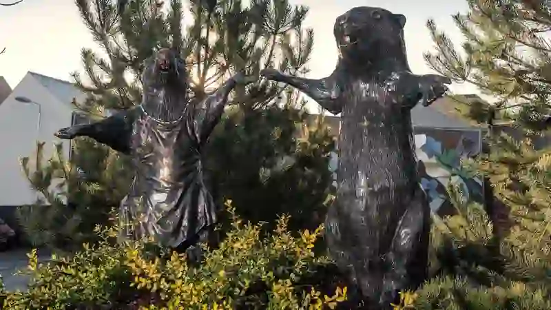 Bronzestatuen von Bibern, die sich an den Händen halten, in den Landschaftsgärten auf dem CS Lewis Square in Belfast.
