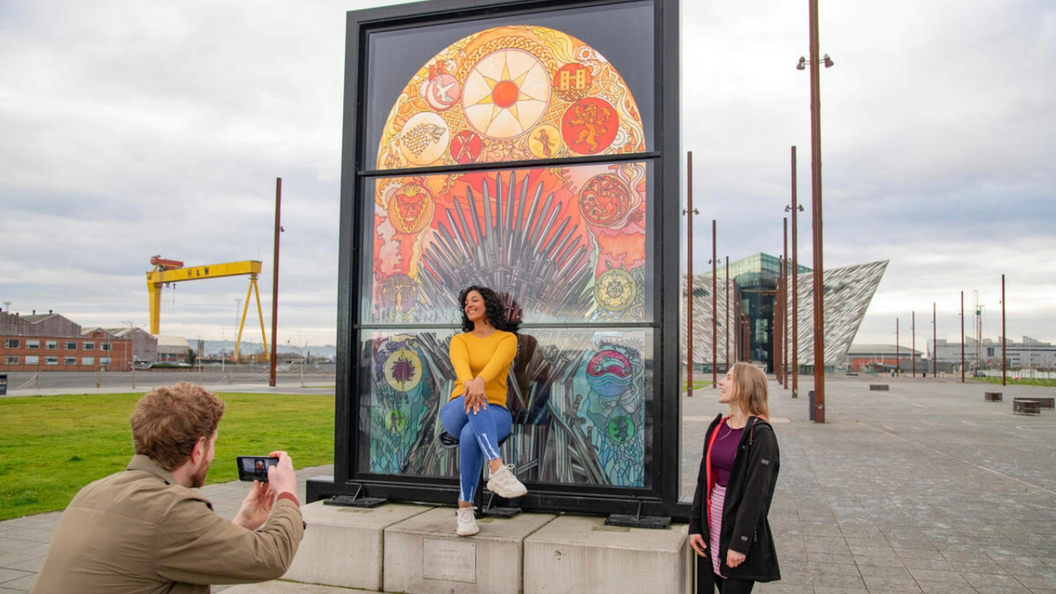 Menschen fotografieren die „Glass of Thrones”-Buntglasfenster in der Nähe des Titanic Belfast.