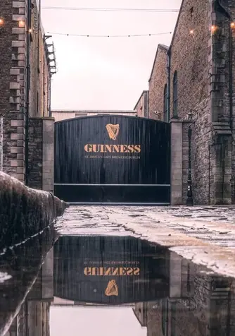 Guinness Storehouse gates at St James’s Gate Brewery in Dublin, with wet cobblestones after rain.