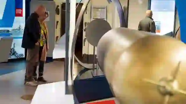 Besucher besichtigen eine Torpedoausstellung im Inneren der HMS Caroline mit interaktiven Museumstafeln in Belfast.