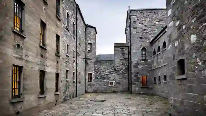Stone courtyard inside Kilmainham Gaol with barred windows and historic prison buildings.